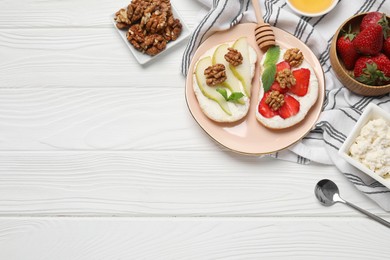 Photo of Plate with different tasty ricotta bruschettas and ingredients on white wooden table, flat lay. Space for text