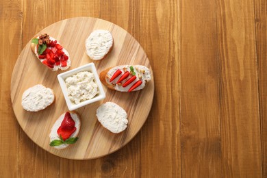 Board with different tasty ricotta bruschettas on wooden table, top view. Space for text