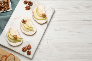 Delicious bruschettas with ricotta cheese, pear and walnuts on white wooden table, flat lay. Space for text