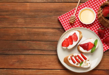 Delicious bruschettas with ricotta cheese, walnuts, mint, strawberries and honey on wooden table, flat lay. Space for text