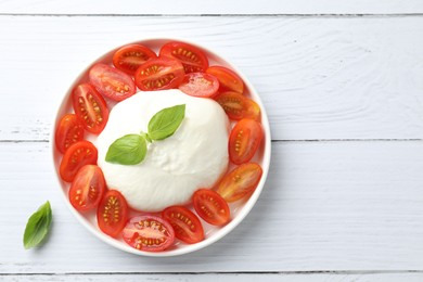 Photo of Delicious burrata cheese, tomatoes and basil on white wooden table, top view. Space for text