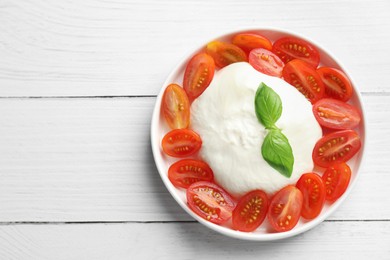 Delicious burrata cheese, tomatoes and basil on white wooden table, top view. Space for text