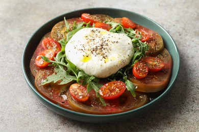 Delicious fresh burrata salad in bowl on gray textured table, closeup