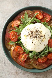 Photo of Delicious fresh burrata salad in bowl on gray textured table, top view