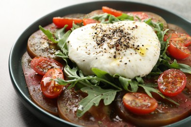 Photo of Delicious fresh burrata salad in bowl on gray table, closeup