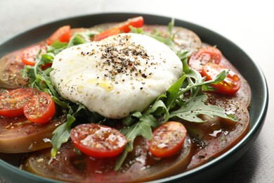 Photo of Delicious fresh burrata salad in bowl on gray table, closeup