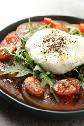 Photo of Delicious fresh burrata salad in bowl on gray table, closeup