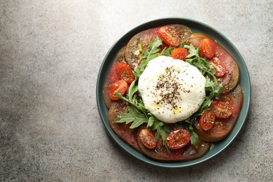 Delicious fresh burrata salad in bowl on gray textured table, top view. Space for text