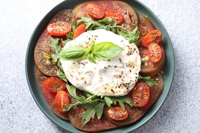 Delicious fresh burrata salad in bowl on light gray textured table, top view