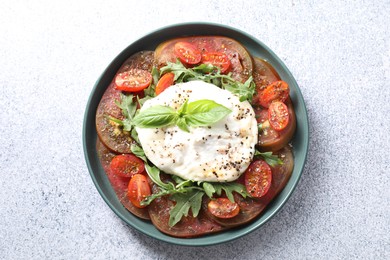 Photo of Delicious fresh burrata salad in bowl on light gray textured table, top view