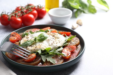 Photo of Delicious fresh burrata salad in bowl served on light gray textured table, closeup