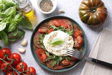 Photo of Delicious fresh burrata salad in bowl served on light gray textured table, flat lay