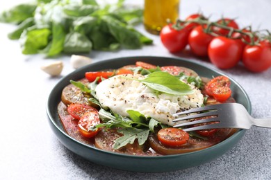 Photo of Delicious fresh burrata salad in bowl served on light gray textured table, closeup