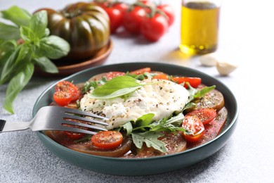 Photo of Delicious fresh burrata salad in bowl served on light gray textured table, closeup