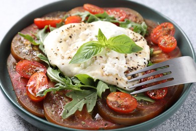 Photo of Delicious fresh burrata salad in bowl served on light gray table, closeup