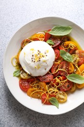 Photo of Delicious fresh burrata salad in bowl on light gray textured table, top view