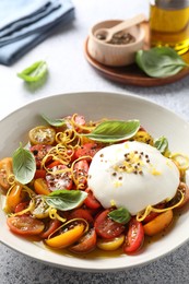 Delicious fresh burrata salad in bowl on light gray table, closeup