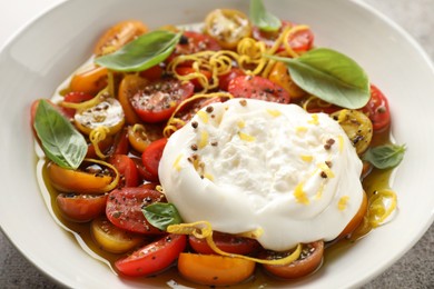 Photo of Delicious fresh burrata salad in bowl on table, closeup