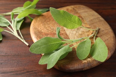 Photo of Green sage leaves on wooden table, closeup