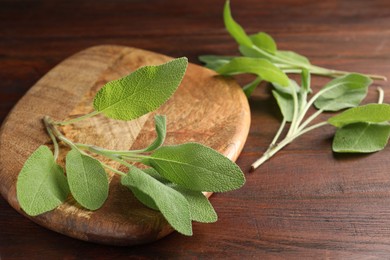 Photo of Green sage leaves on wooden table, closeup