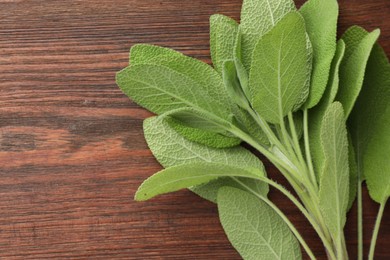 Photo of Green sage leaves on wooden table, top view. Space for text