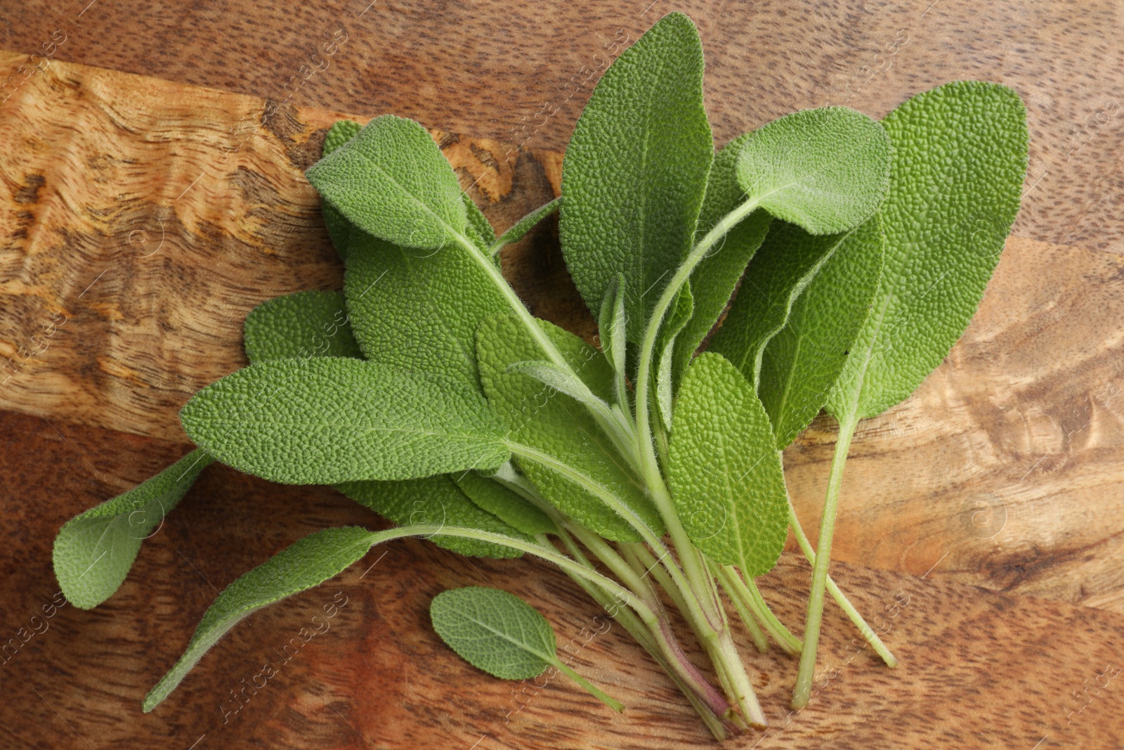 Photo of Green sage leaves on wooden table, top view