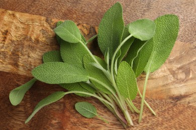 Photo of Green sage leaves on wooden table, top view