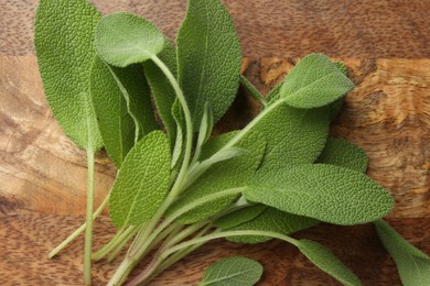 Photo of Green sage leaves on wooden table, top view