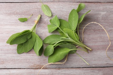 Photo of Green sage leaves on color wooden table, flat lay