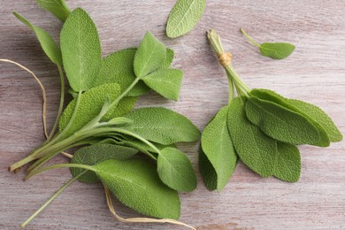 Photo of Green sage leaves on color wooden table, flat lay