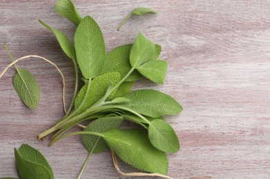 Photo of Green sage leaves on color wooden table, flat lay. Space for text