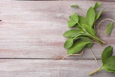 Photo of Green sage leaves on color wooden table, flat lay. Space for text