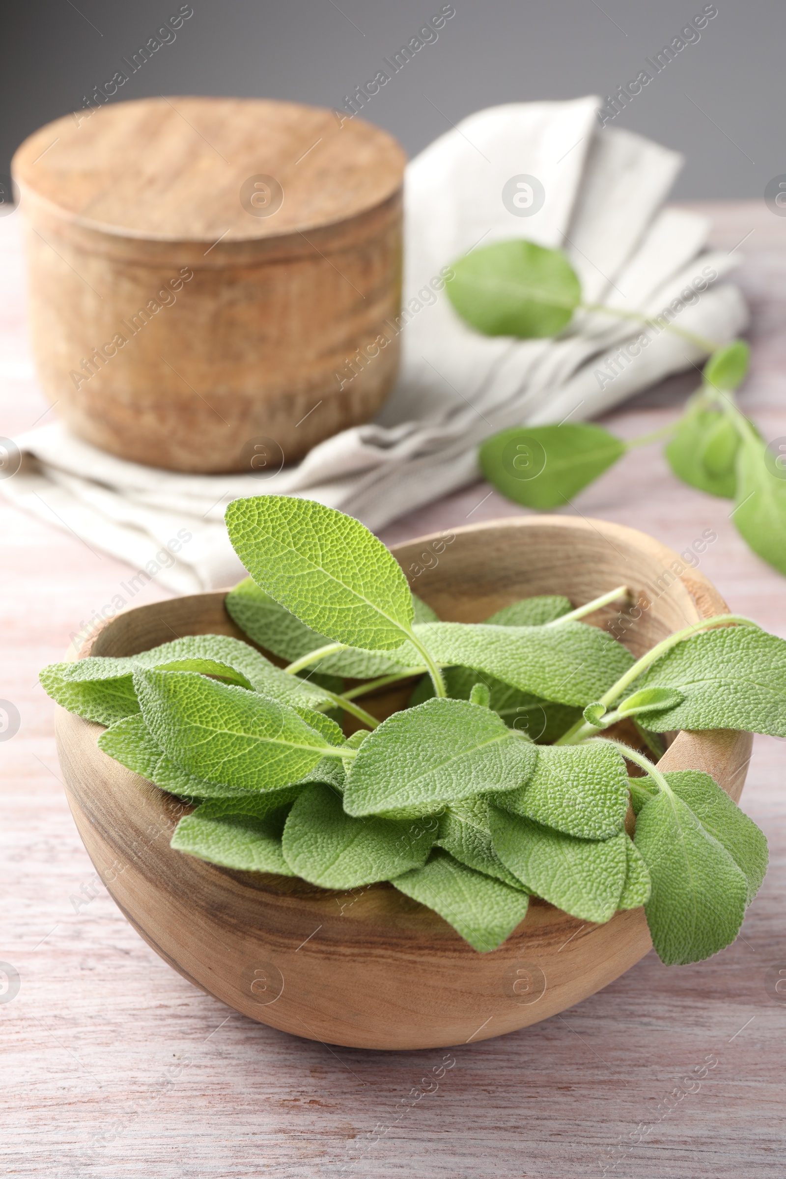 Photo of Green sage leaves in bowl on color wooden table