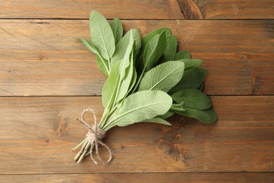 Photo of Bunch of green sage leaves on wooden table, top view