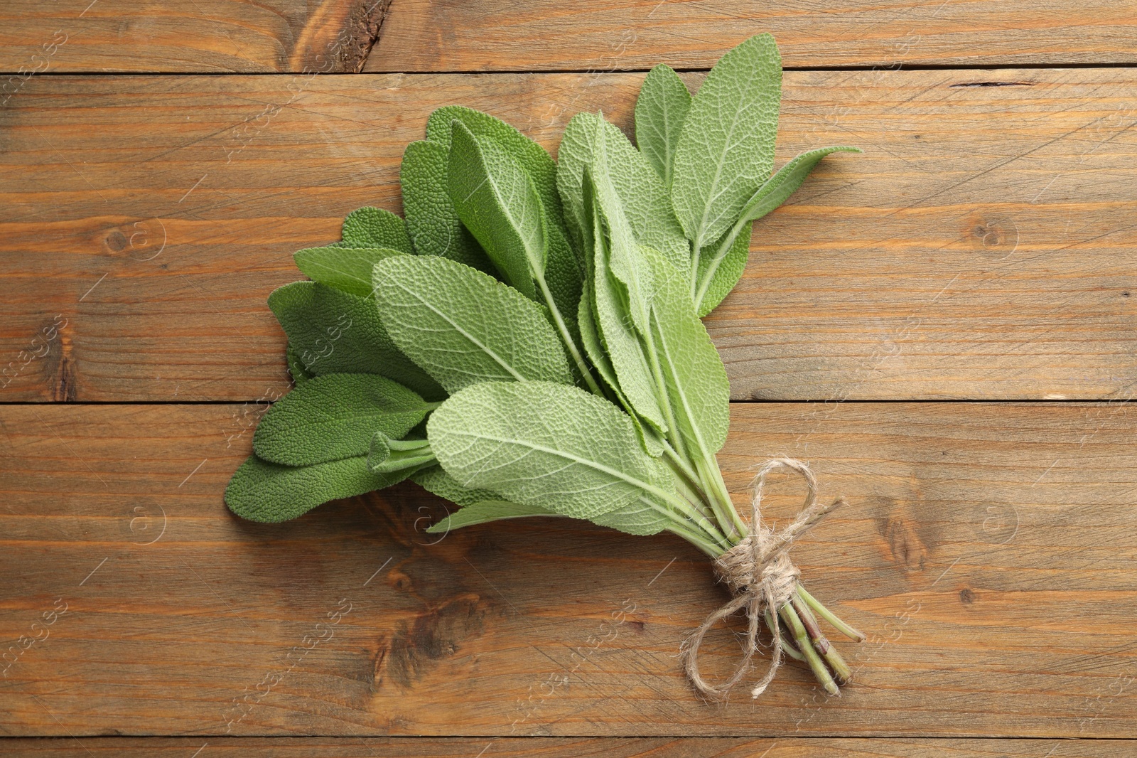 Photo of Bunch of green sage leaves on wooden table, top view