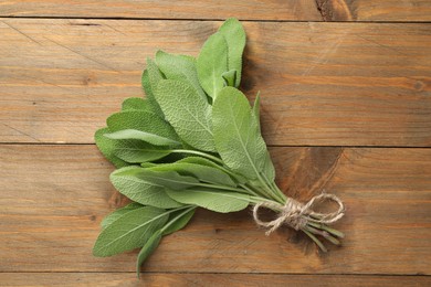 Photo of Bunch of green sage leaves on wooden table, top view