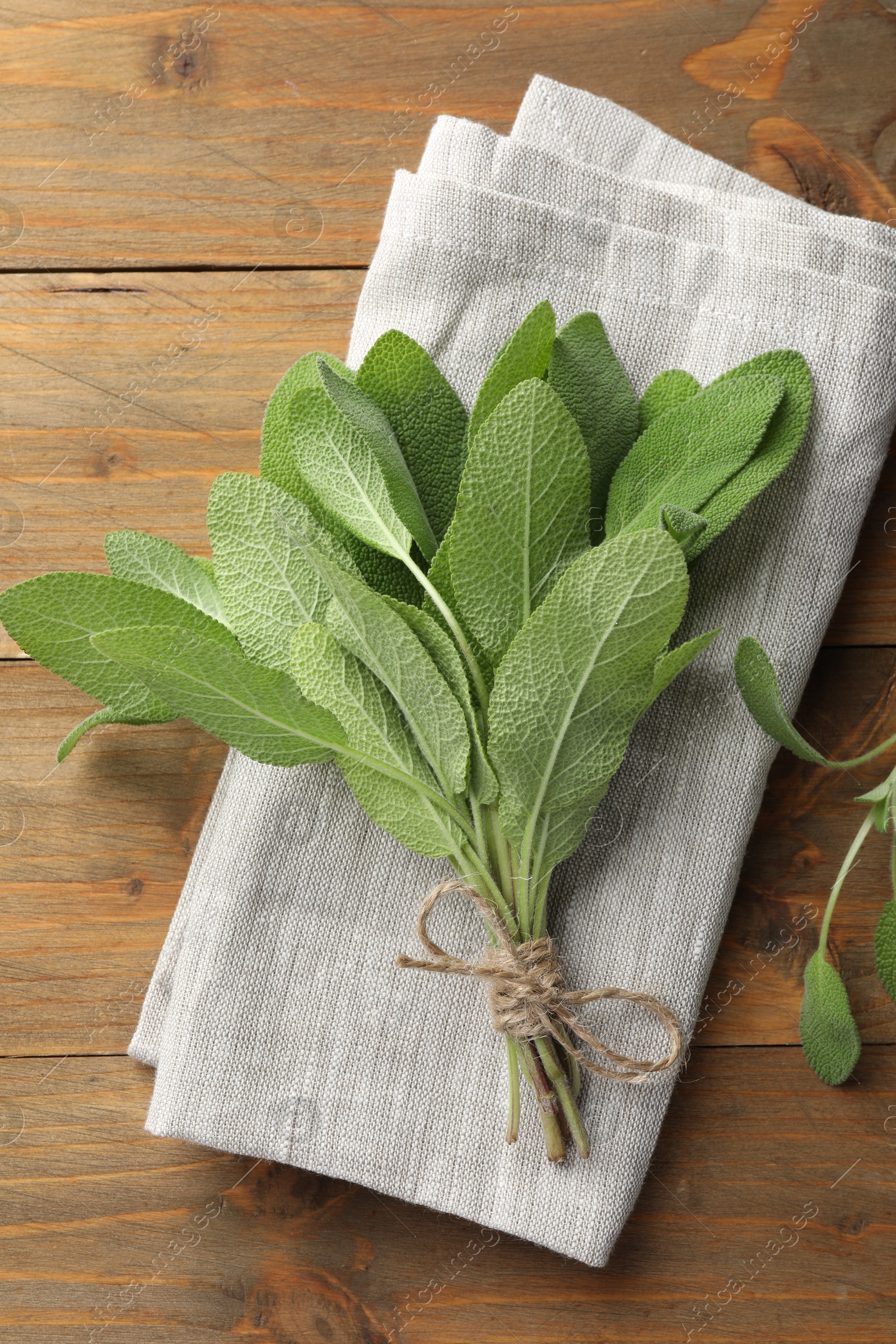 Photo of Bunch of green sage leaves on wooden table, top view