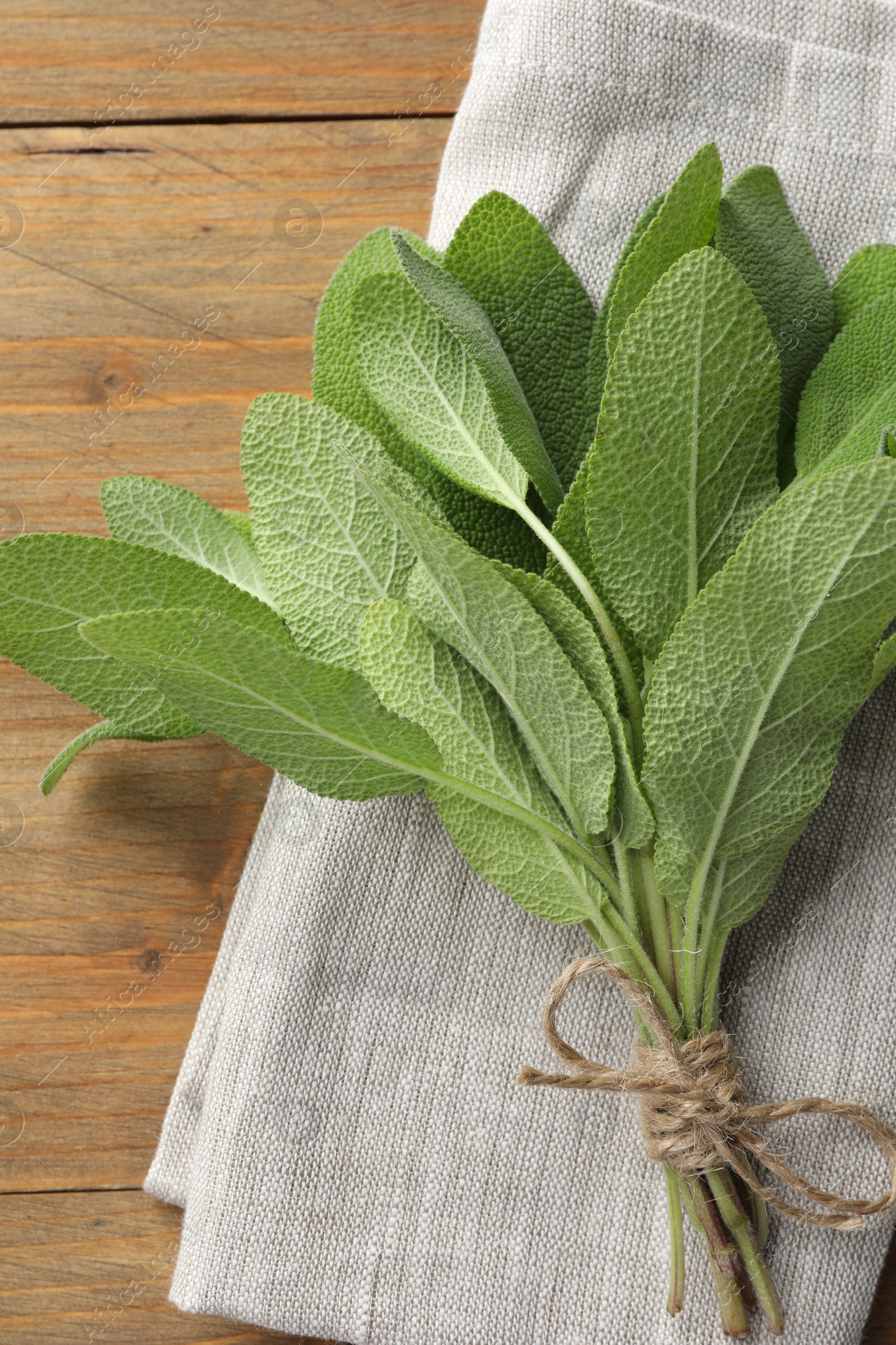 Photo of Bunch of green sage leaves on wooden table, top view