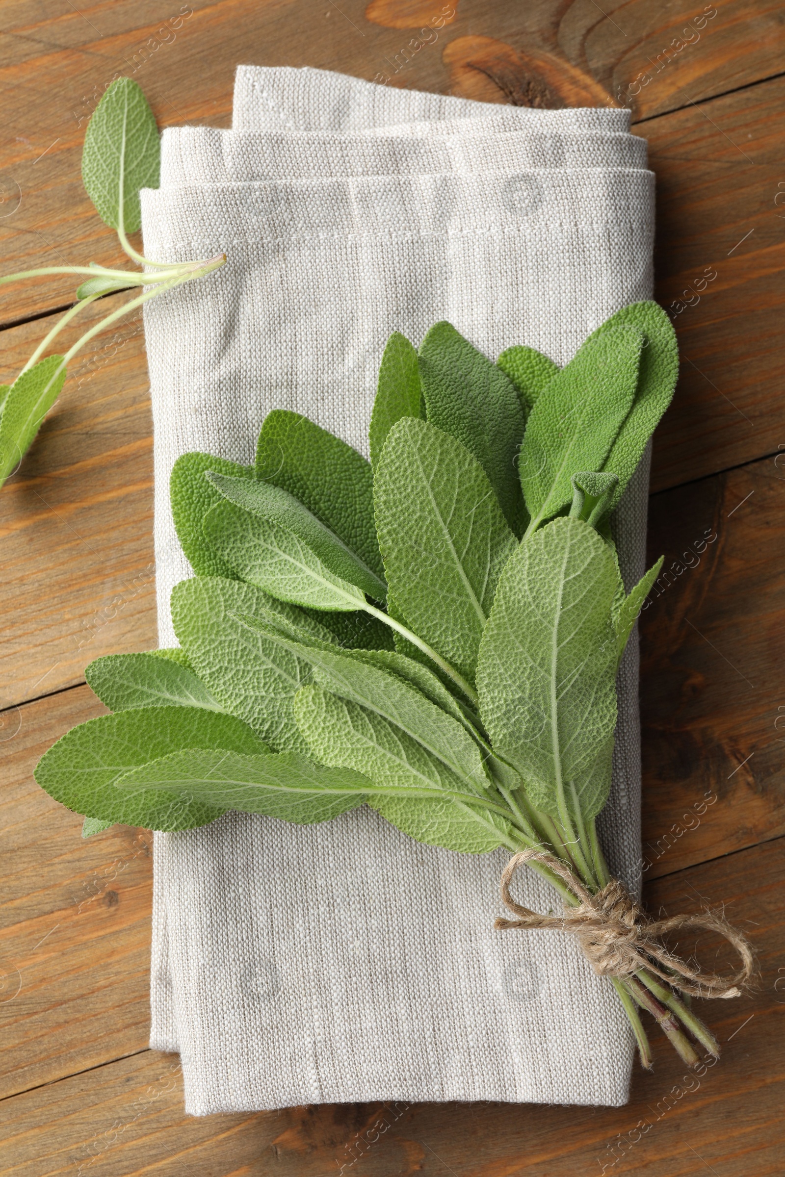 Photo of Bunch of green sage leaves on wooden table, top view