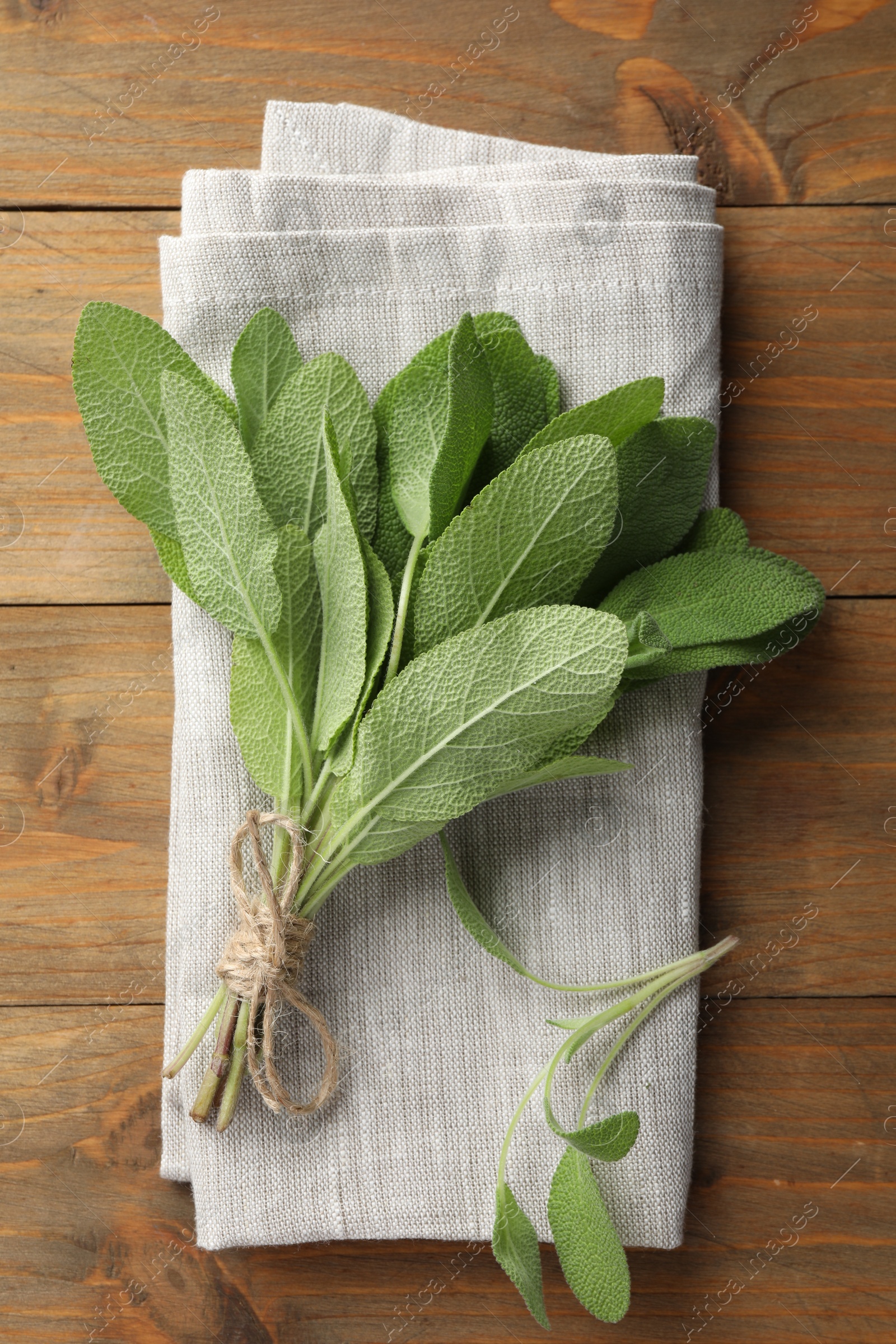 Photo of Bunch of green sage leaves on wooden table, top view