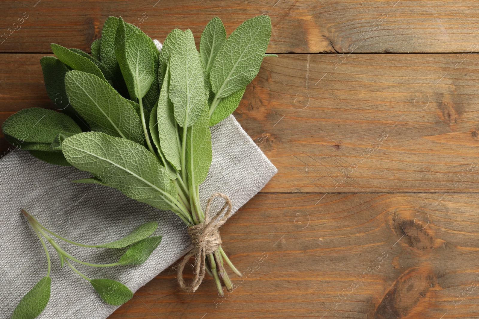 Photo of Bunch of green sage leaves on wooden table, top view. Space for text