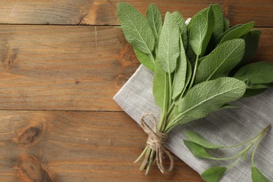 Photo of Bunch of green sage leaves on wooden table, top view. Space for text