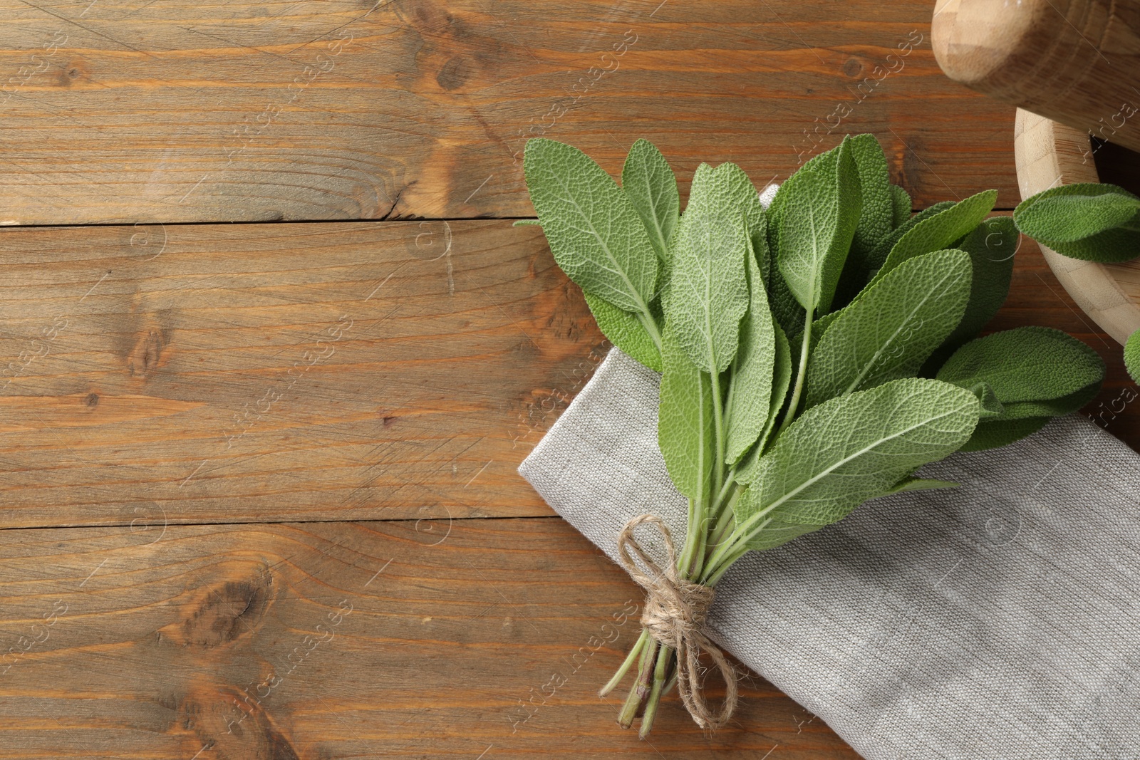 Photo of Bunch of green sage leaves on wooden table, flat lay. Space for text