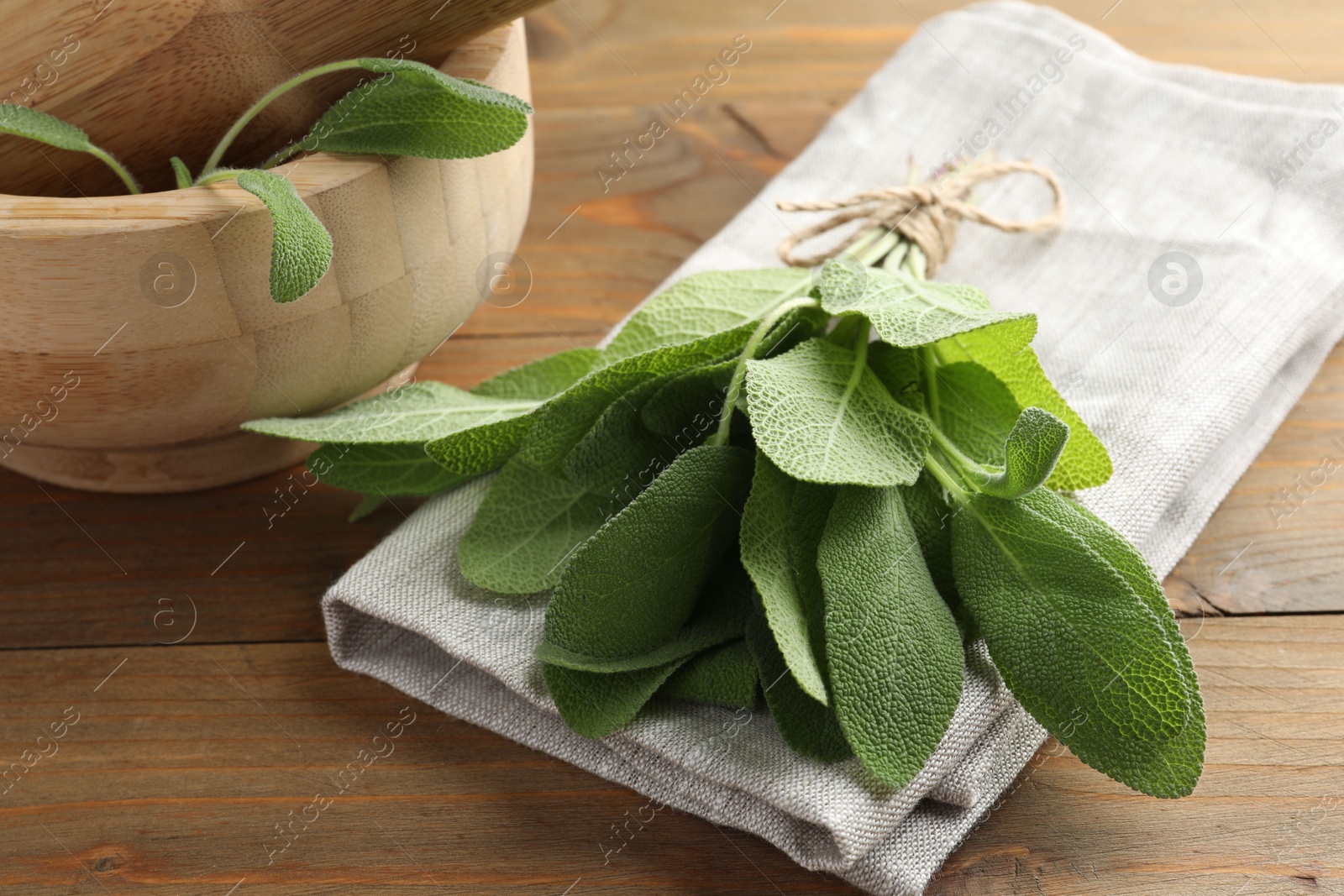 Photo of Bunch of green sage leaves on wooden table, closeup