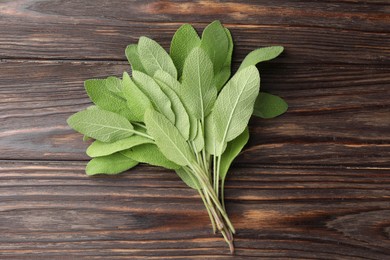 Photo of Green sage leaves on wooden table, top view