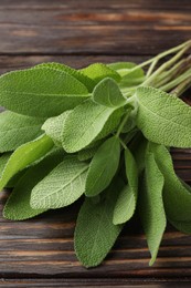 Photo of Green sage leaves on wooden table, closeup