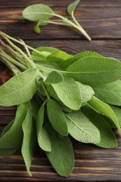 Photo of Green sage leaves on wooden table, closeup