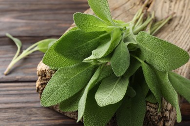 Photo of Green sage leaves on wooden table, closeup