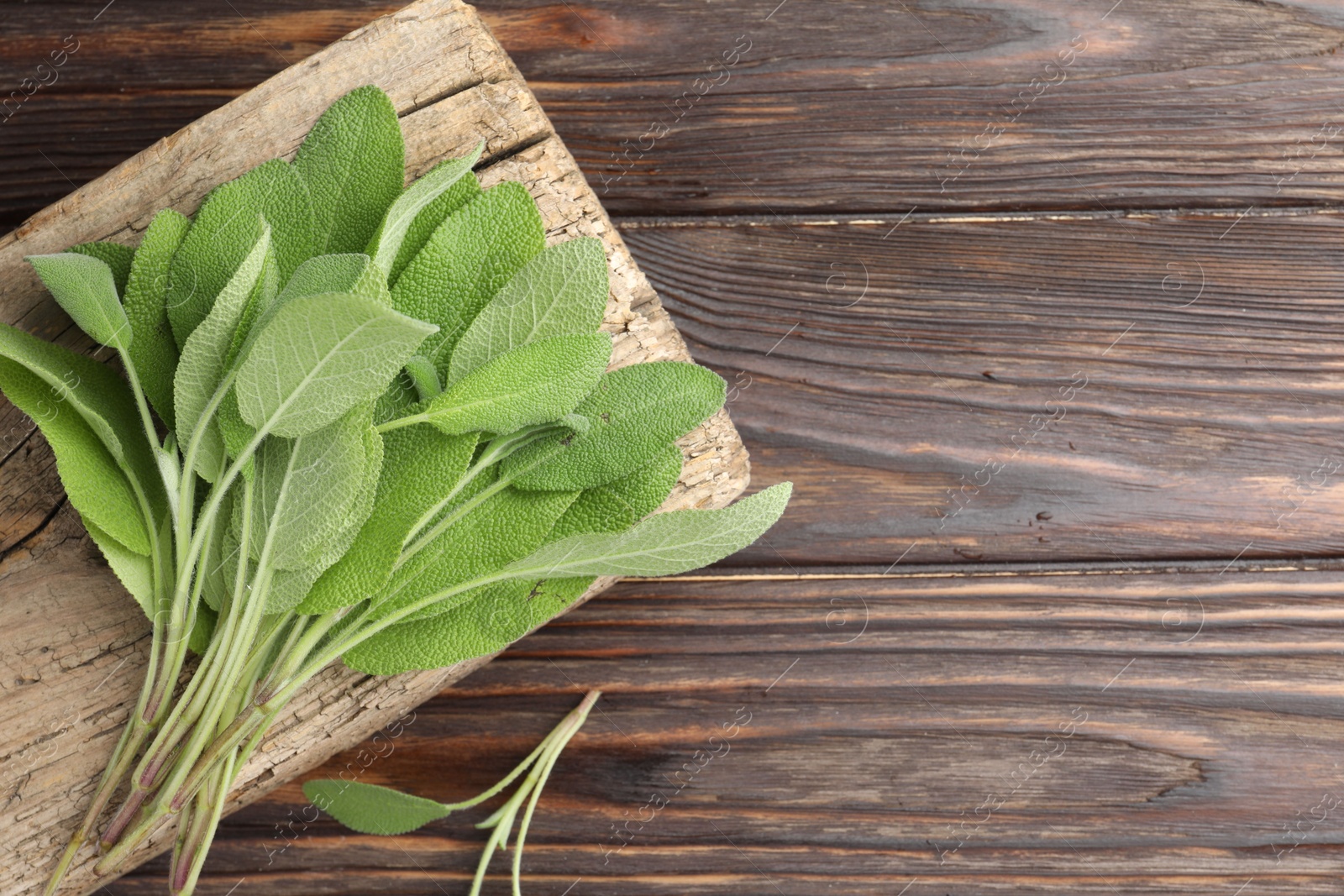 Photo of Green sage leaves on wooden table, top view. Space for text