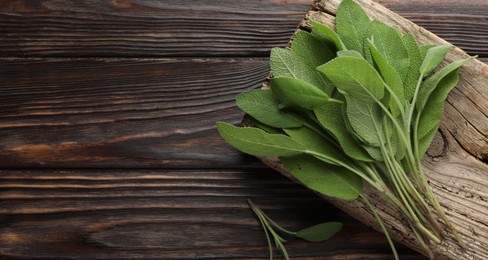 Photo of Green sage leaves on wooden table, top view. Space for text